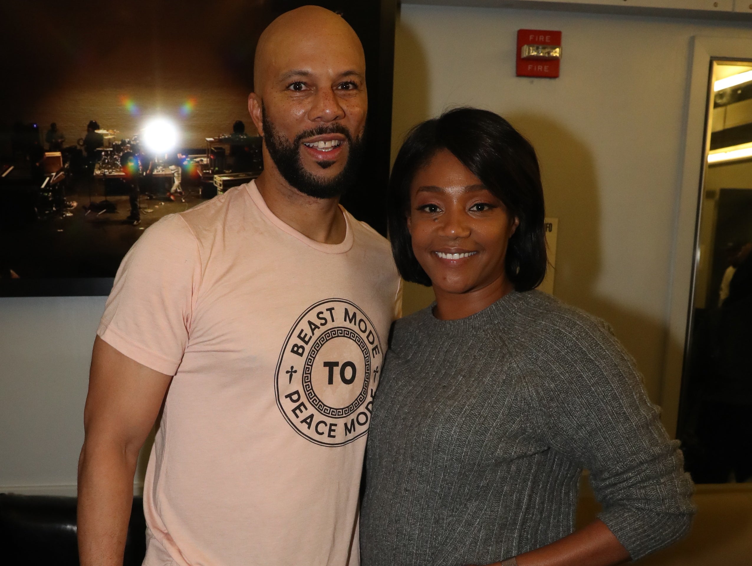 Common and Tiffany have their arms around each other backstage at an event