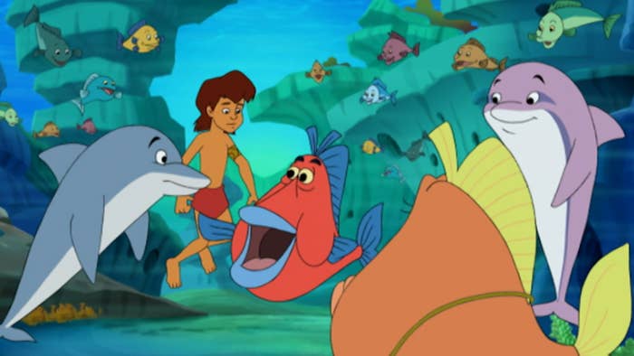 A young boy surrounded by sea creatures while underwater, including dolphin and fish 