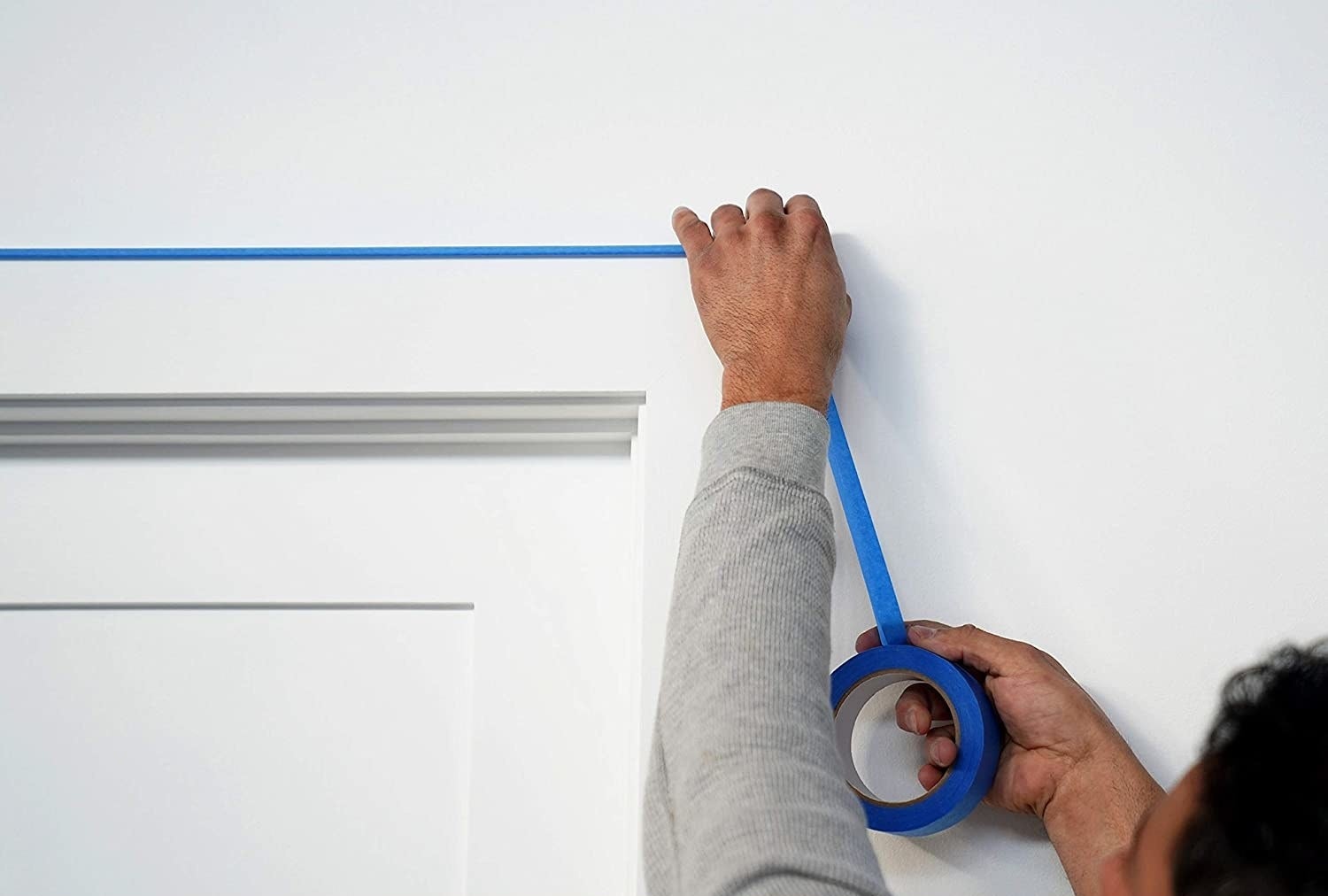 a model sticking the blue tape to a wall