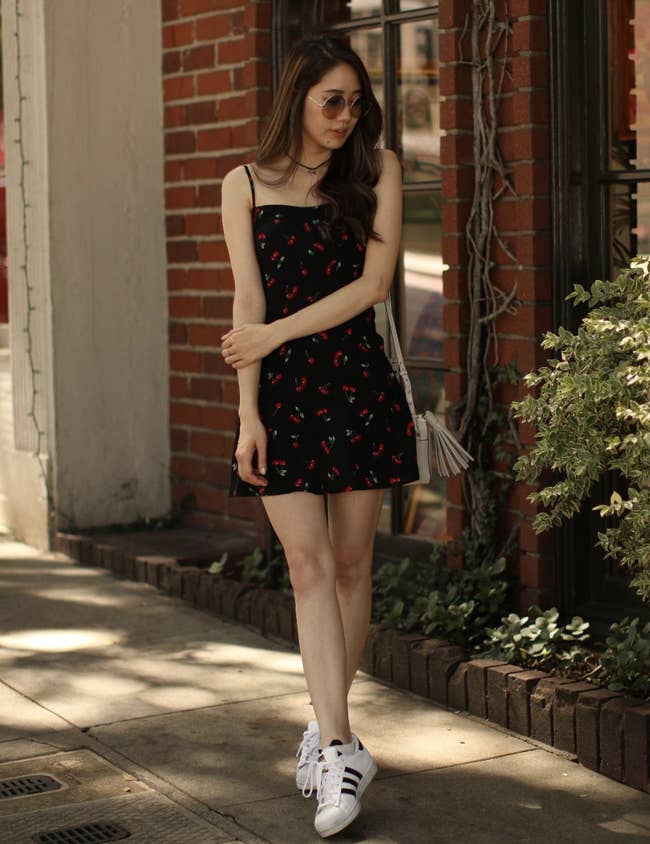 reviewer wearing black mini dress with cherry print 
