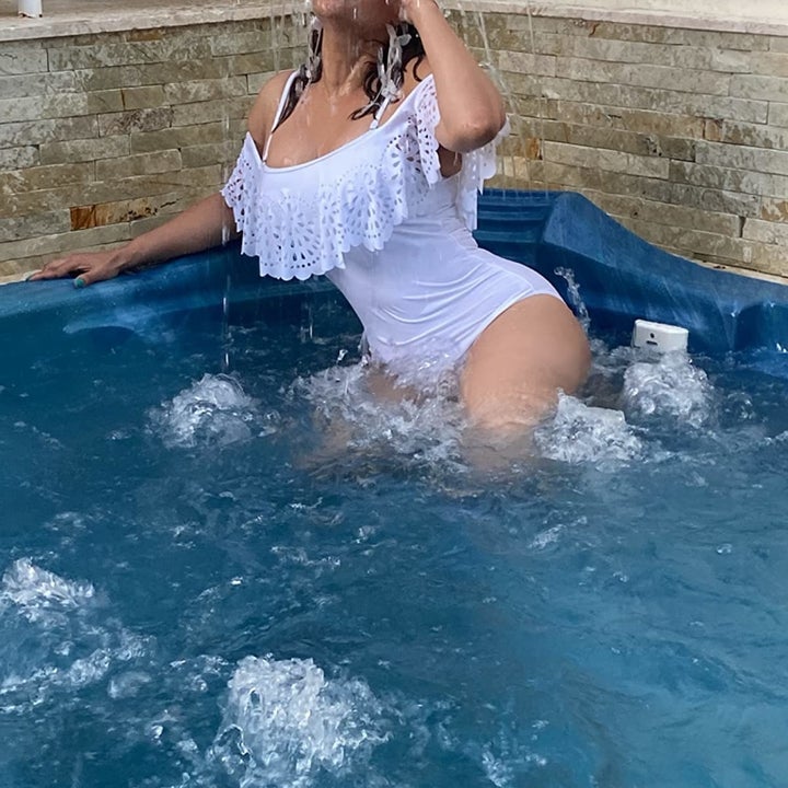 reviewer photo wearing white swimsuit in pool with water falling on head