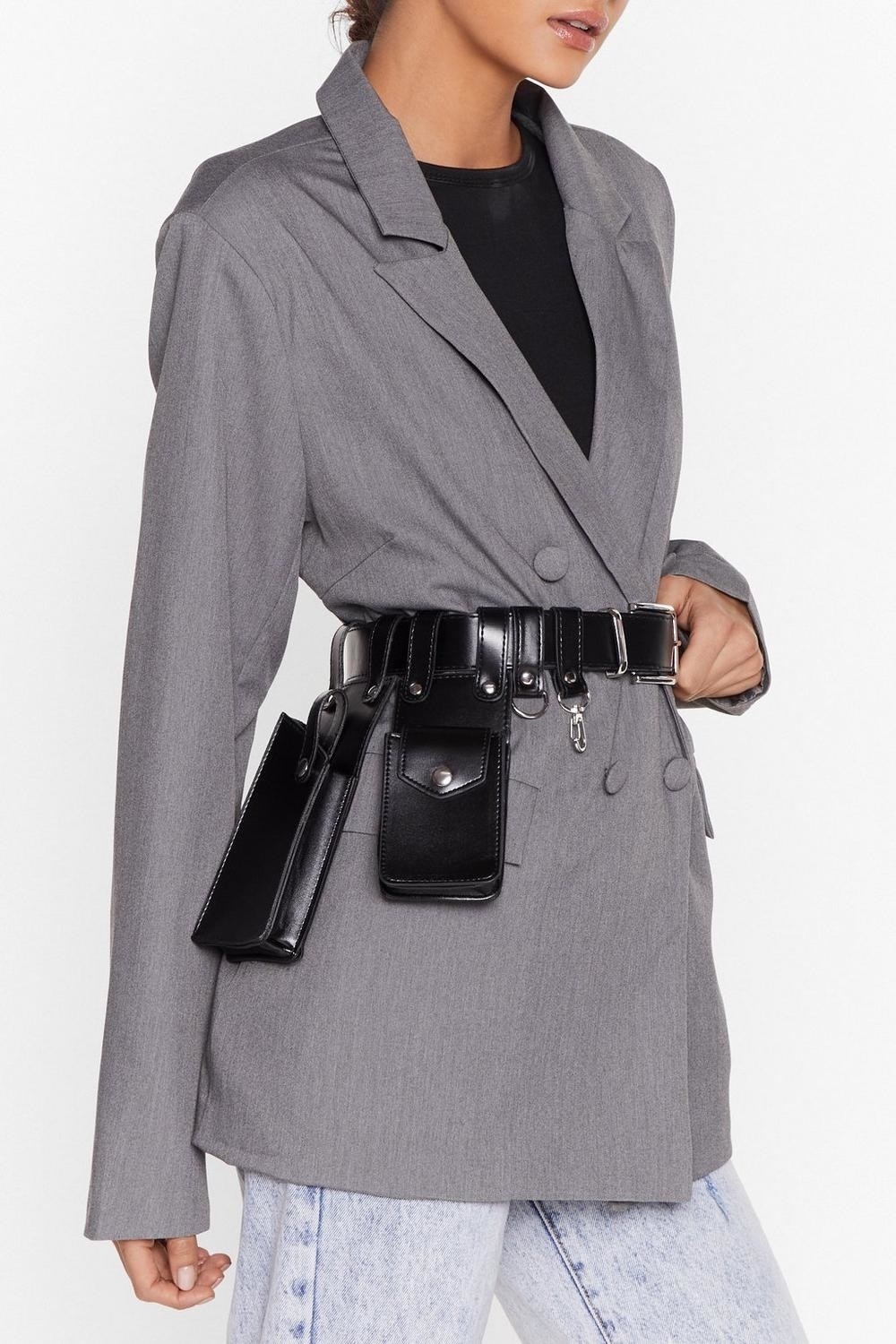 A person wearing the stylish utility belt around their waist over an oversized suit jacket