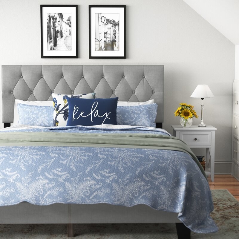the gray bed with blue bedding a pillow that says &quot;relax&quot;