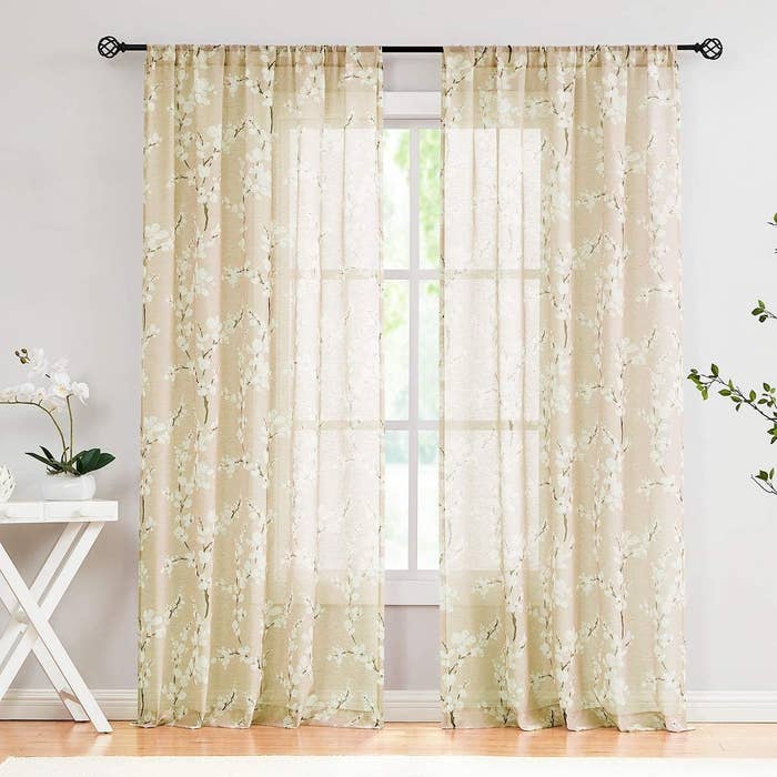 A set of sheer curtains on a bright window with small flowers patterned on them 