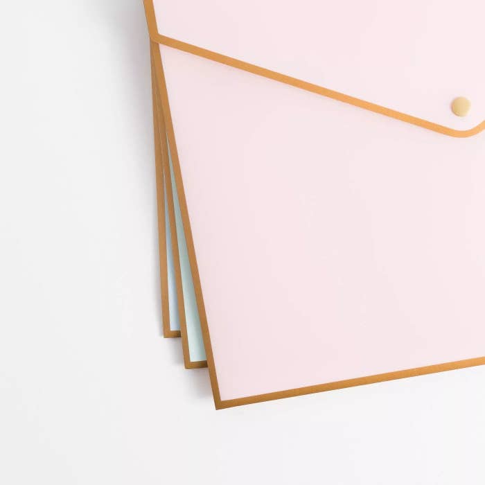 Three document folders in pastel blue and pink. They all have gold trim and snap closures.