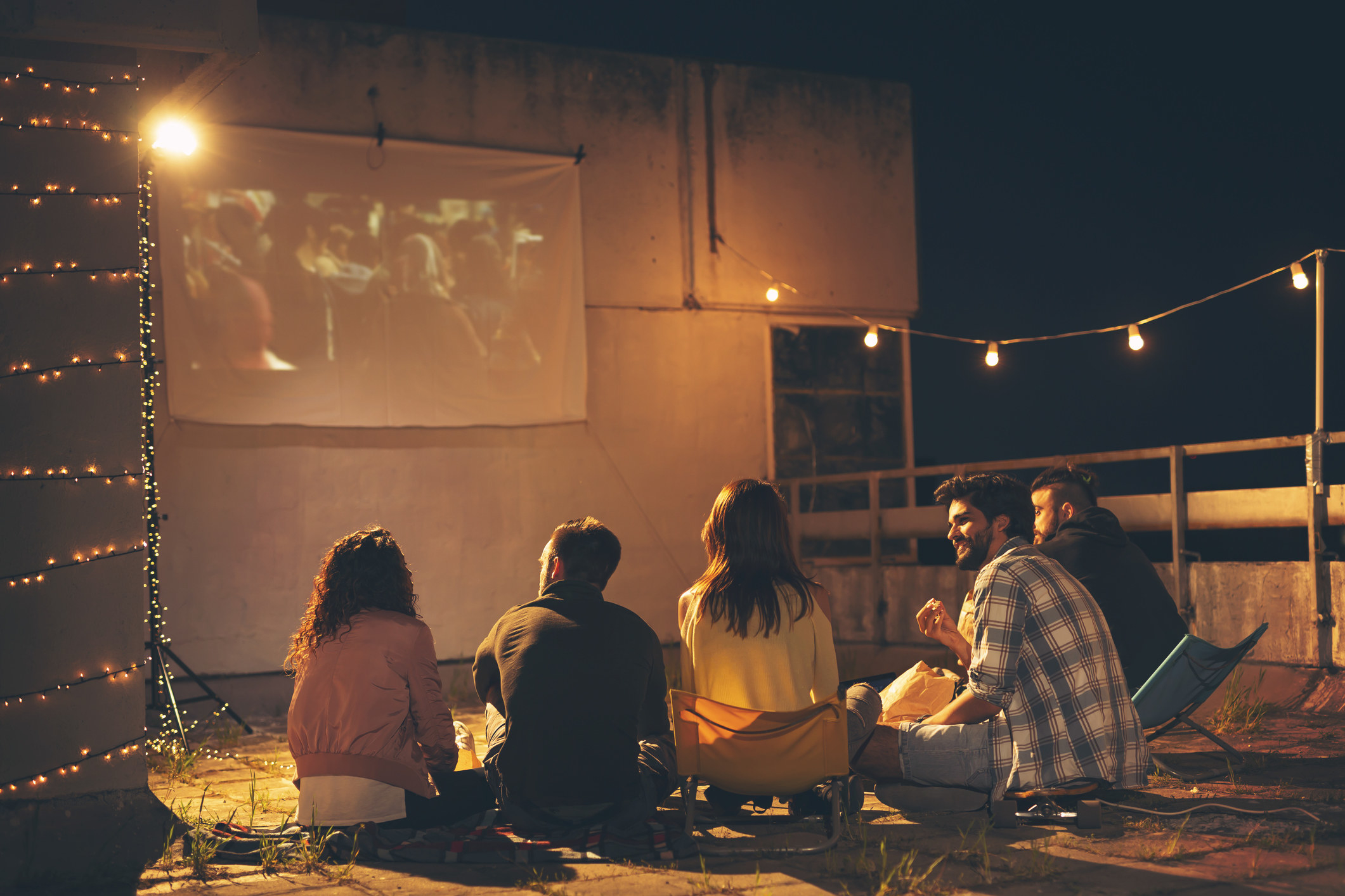 Friends watching a movie on a projector screen.