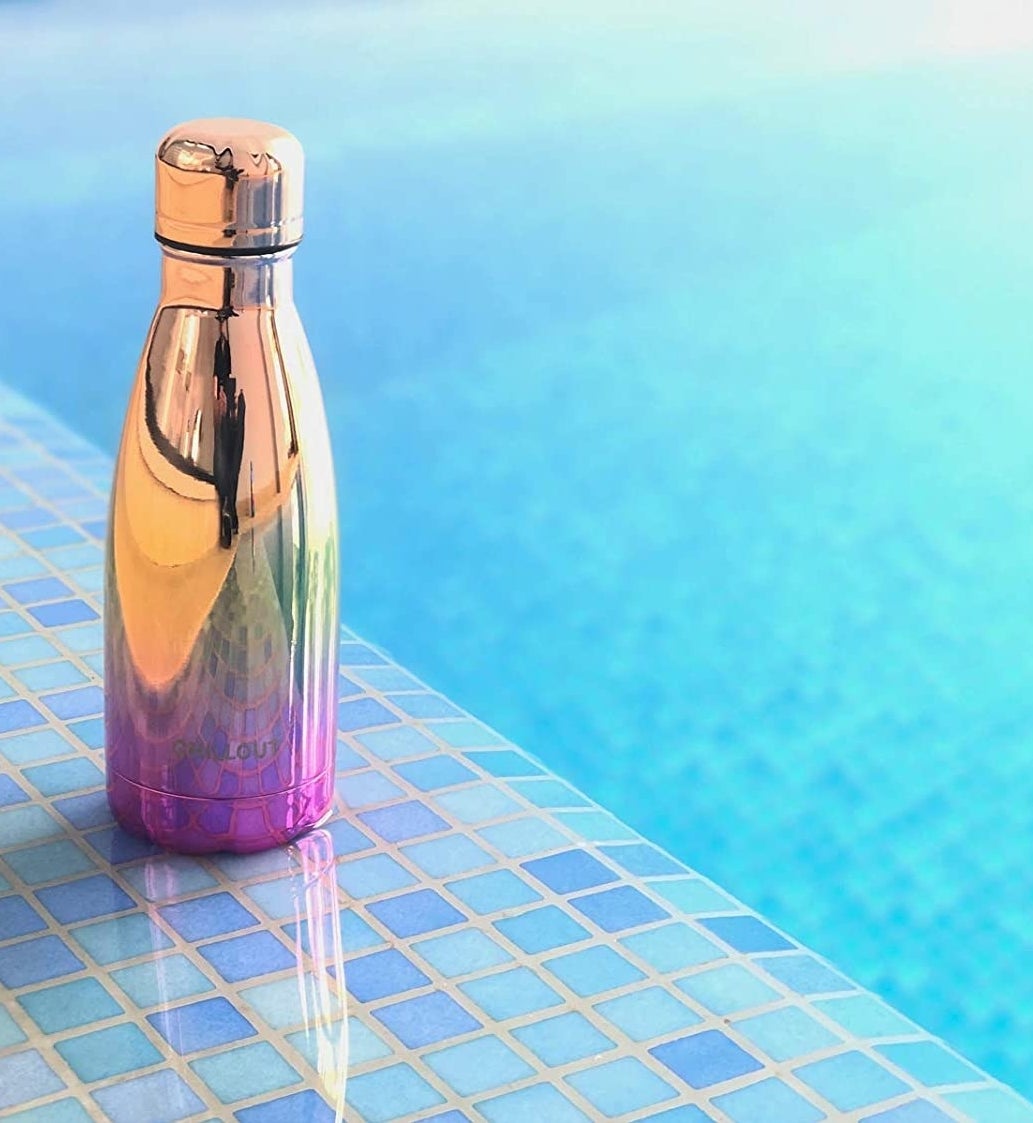 The shiny waterbottle on the edge of a pool 