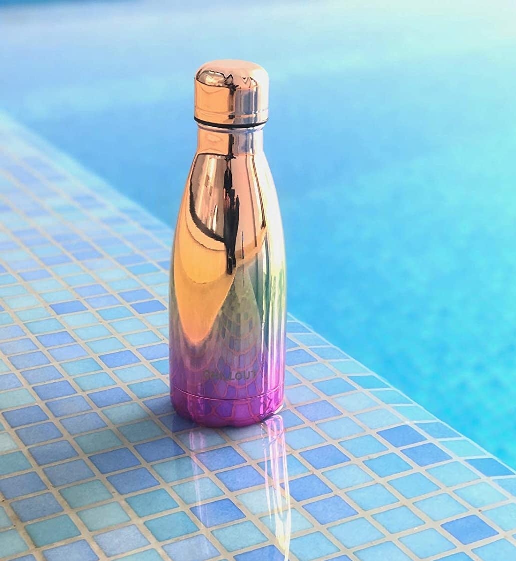 The shiny waterbottle on the edge of a pool 