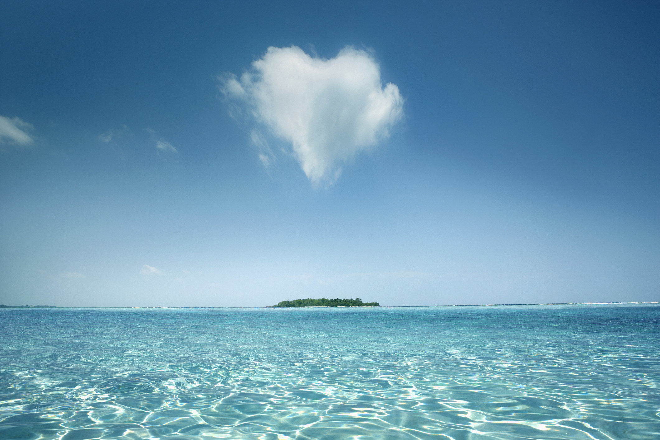 An image of a heart-shaped cloud above an ocean