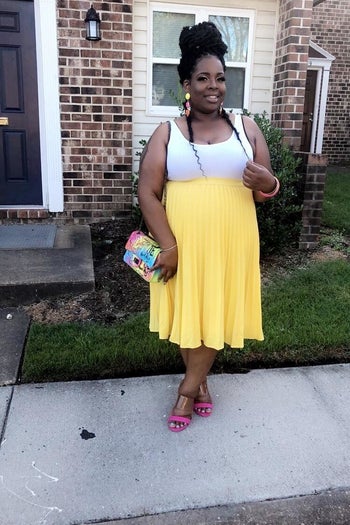 reviewer wearing the skirt in yellow with a white tank and heels 