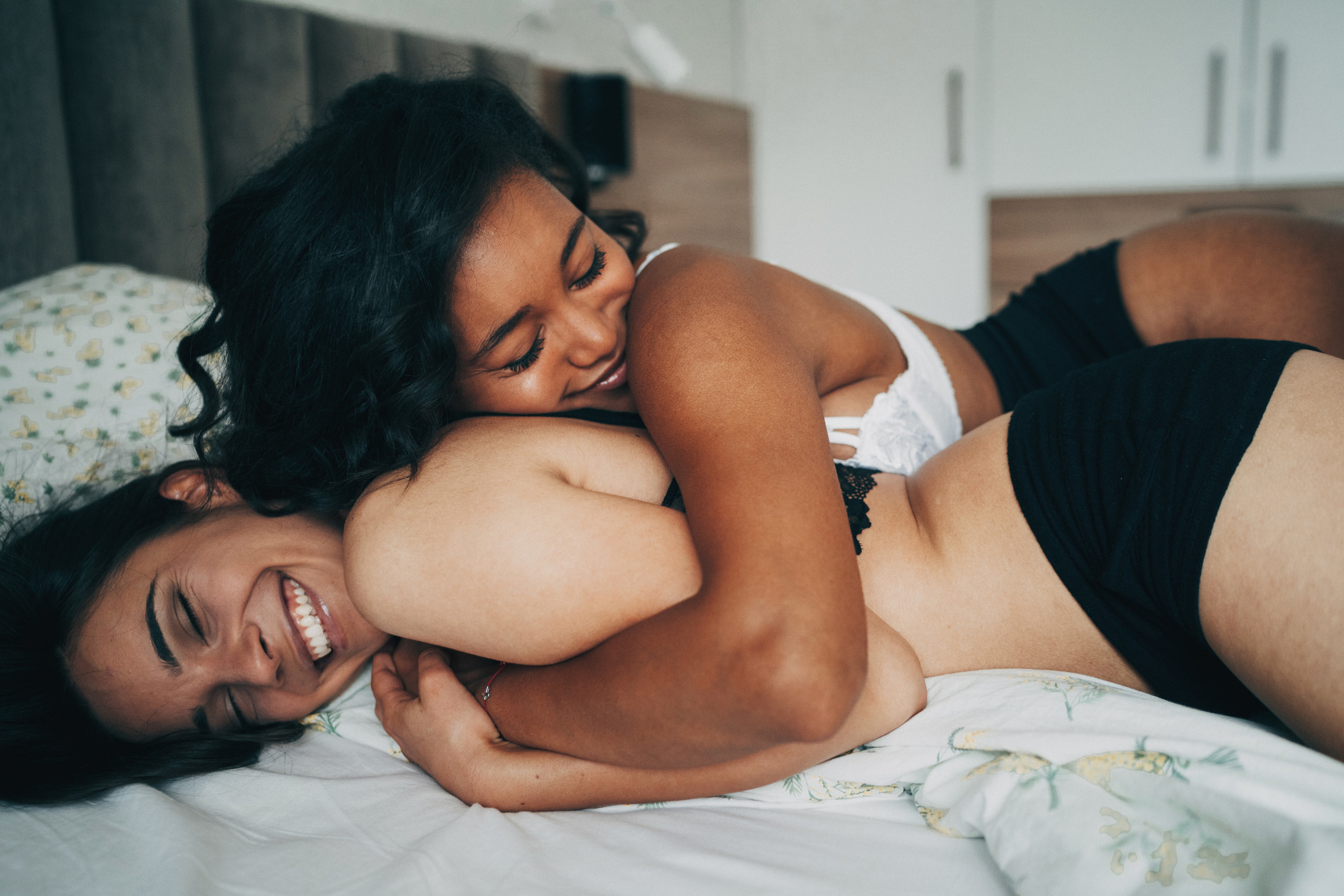 An image of two women embracing in bed