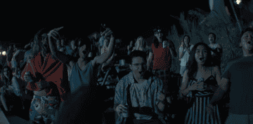 High schoolers at a lake at night cheering on their friend