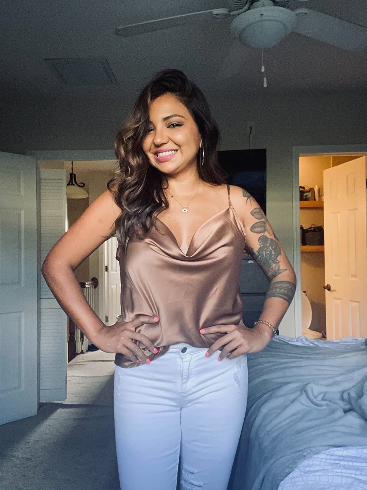reviewer wears the khaki colored v-neck satin cami with white jeans