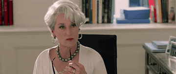 Meryl Streep in The Devil Wears Prada sitting at her desk and musing