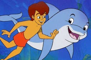 A young boy and dolphin smiling at each other while they swim underwater