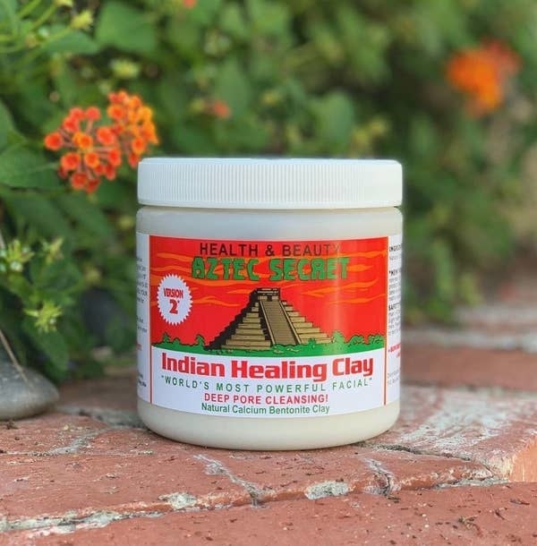 Jar of Indian Healing Clay on brick near flowers