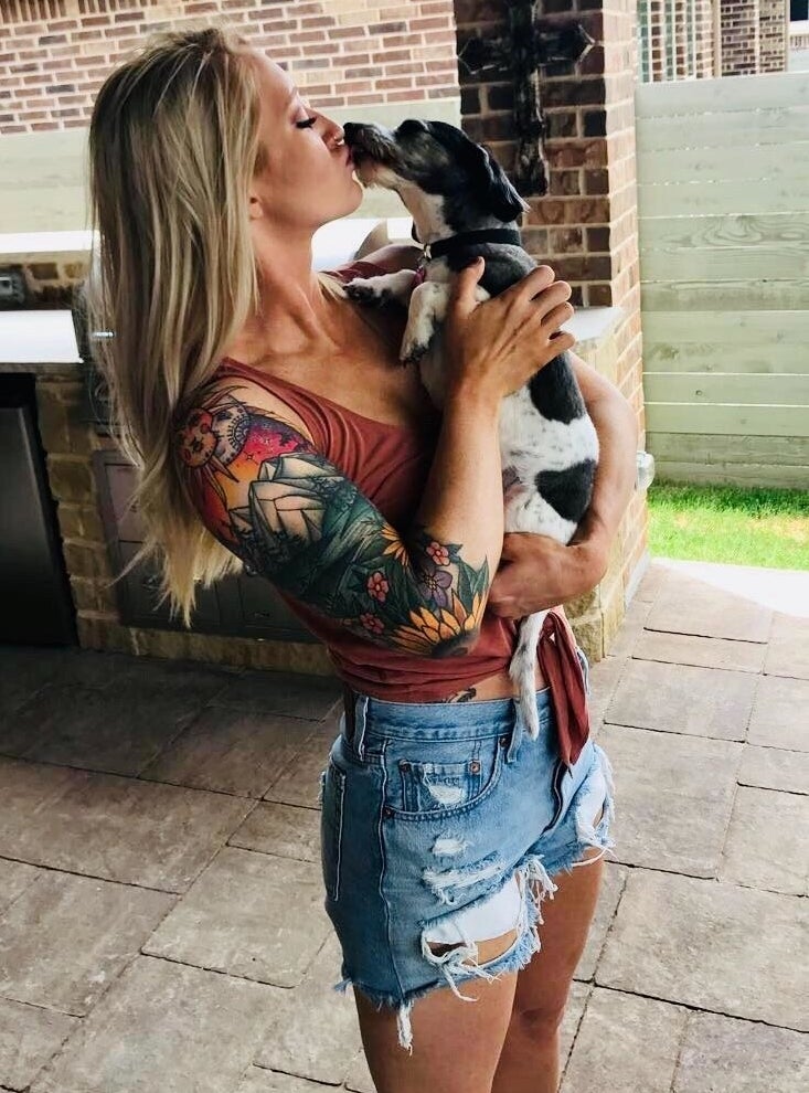 A reviewer holds a dog while wearing the blue denim distressed shorts.