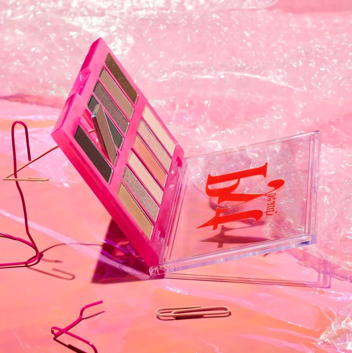 Open palette surrounded by paper clips against pink set