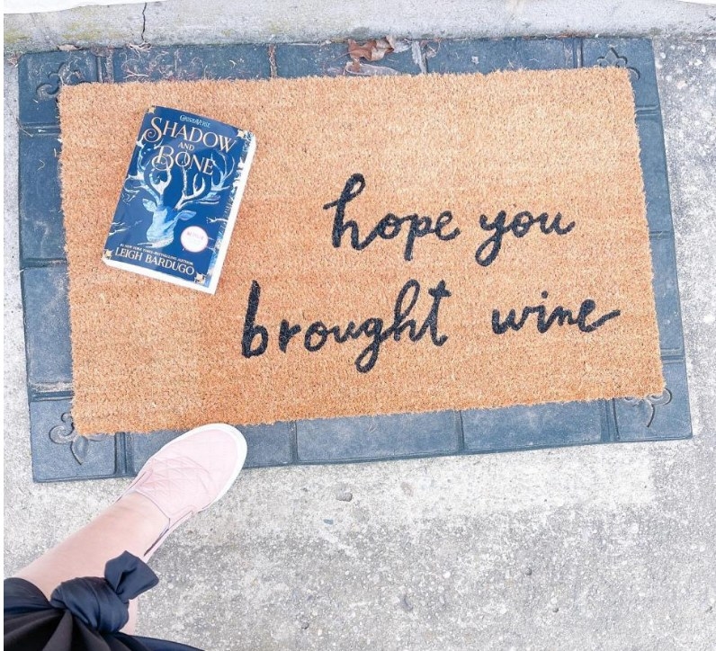 A 18&quot; x 30&quot;, black and tan doormat that reads, &quot;hope your brought wine&quot; 
