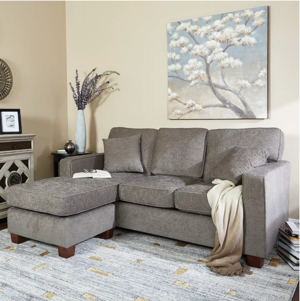 A taupe sectional sofa with a reversible chaise and two matching pillows displayed in a living room
