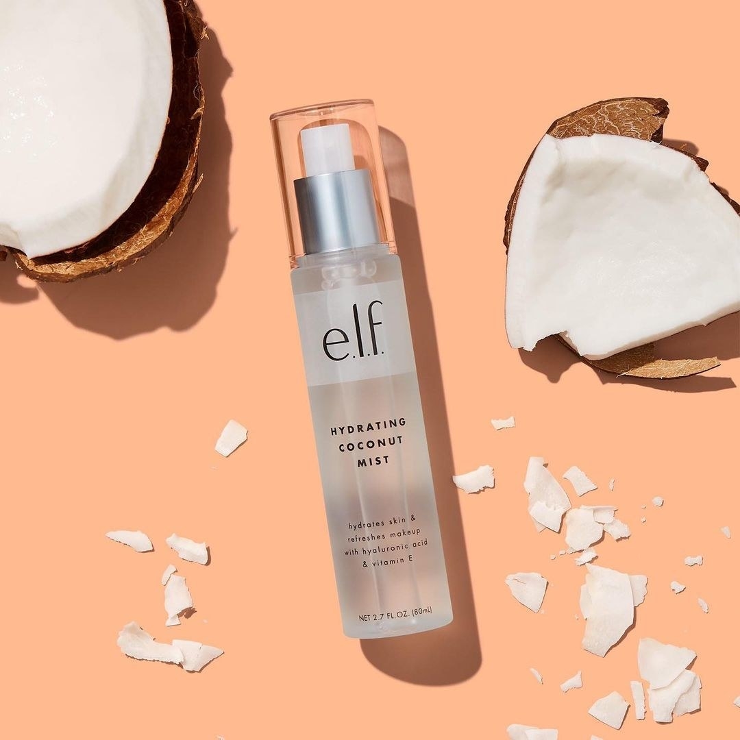 elf coconut mist laying against peach background next to broken coconut pieces