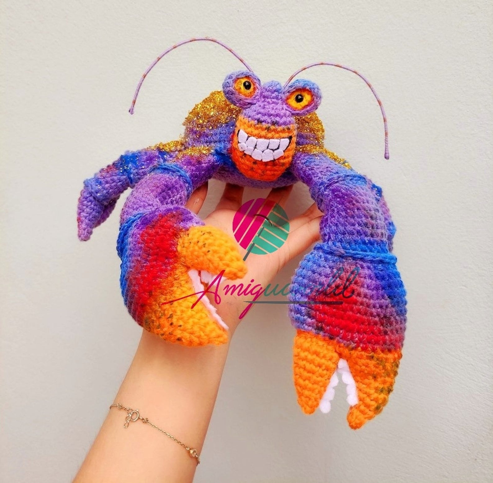 stuffed crocheted lobster shaped like Tamatoa from Moana. It&#x27;s purple, orange, and red.