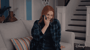 Wanda from &quot;WandaVision&quot; gives a cheeky smile as she turns on the TV with a remote
