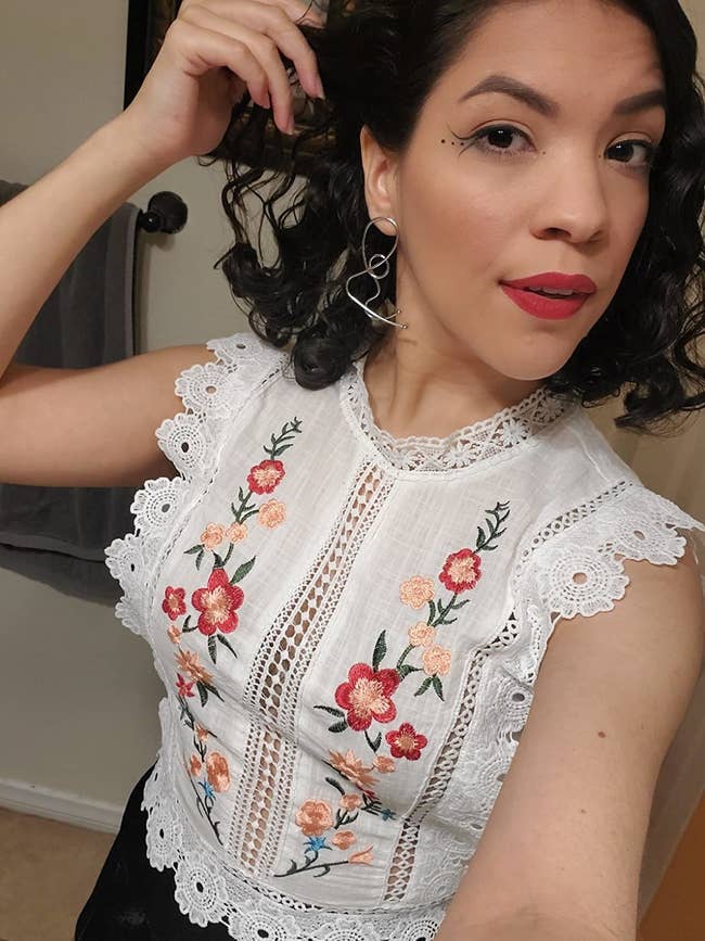 reviewer wearing white top with scallop lace trim and red and pink embroidered flowers