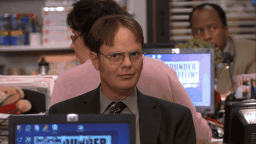 A mischievous Dwight from &quot;The Office&quot; raises his brows as he shushes the camera