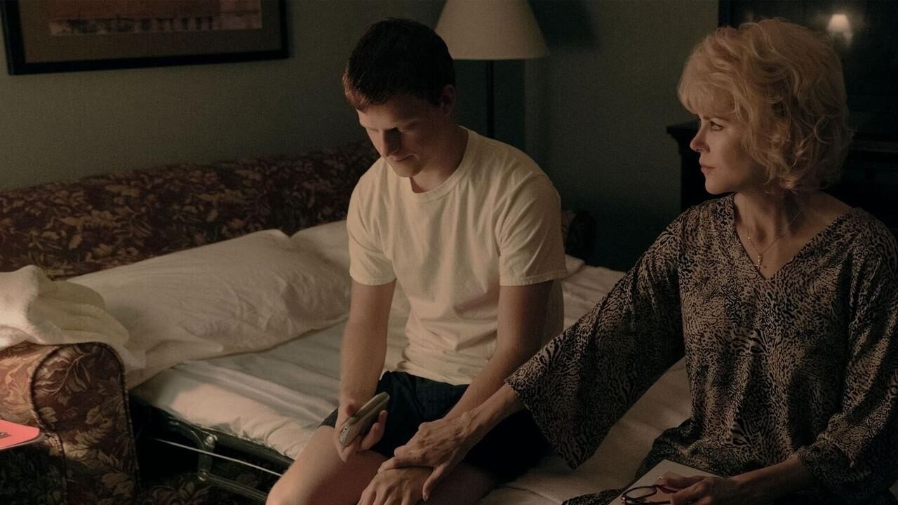 Lucas Hedges as Jared Eamons and Nicole Kidman as his mother sitting on a bed together, while Kidman puts a hand on his knee to comfort him