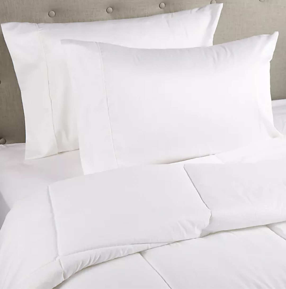 A white box-stitched comforter on a bed 