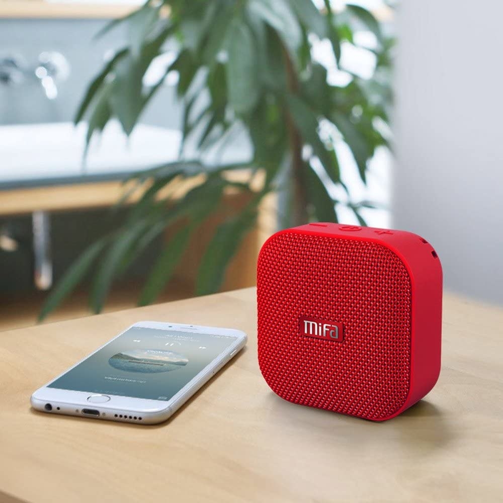 The speaker on a desk beside a cellphone