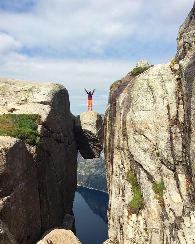 Someone standing on a suspended boulder in Kjeragbolten, Norway