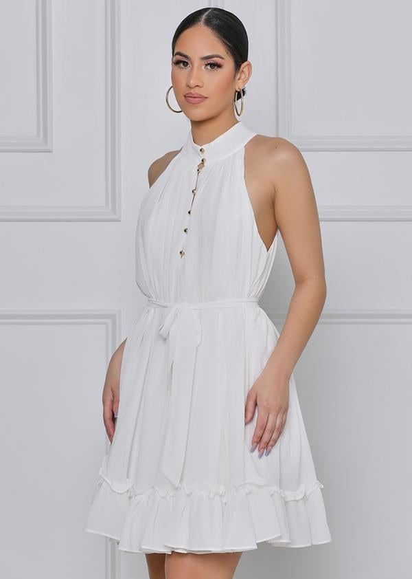 a model wearing a sleeveless halter top dress in white with a full frilly skirt and buttons up the front 