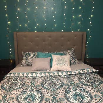 Reviewer hangs same light curtain on teal wall above their gray bed
