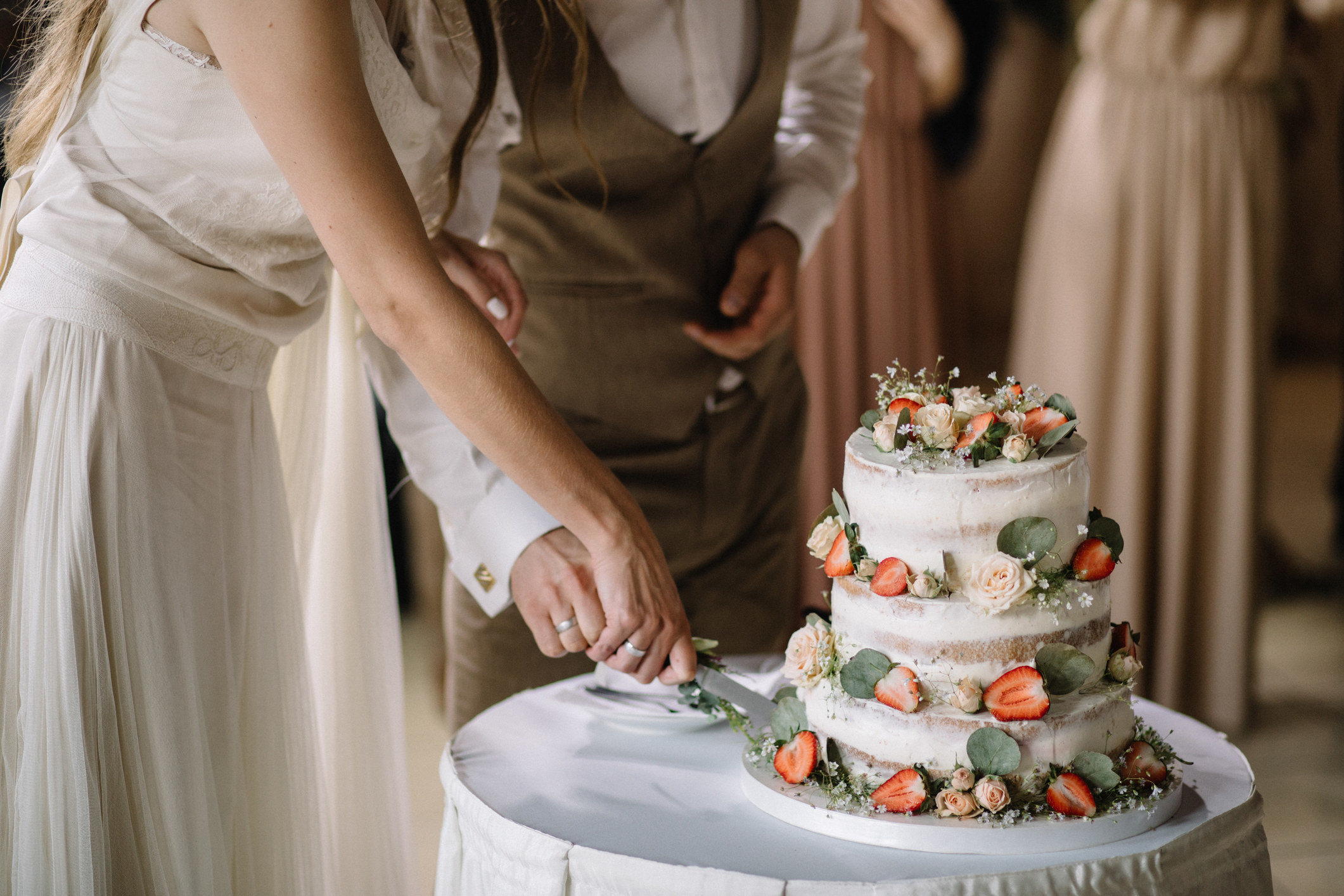 A bride and a groom is cutting their wedding cake