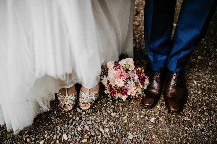 A top view of a bride and groom&#x27;s shoes and bouquet