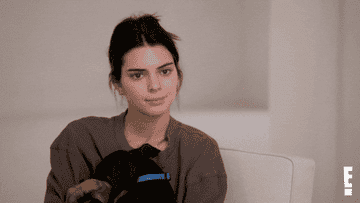 Kendall Jenner reacting to someone offscreen while holding her dog