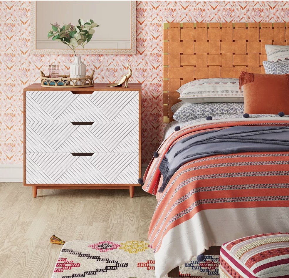 A white and brown, three-drawer dresser in a bedroom