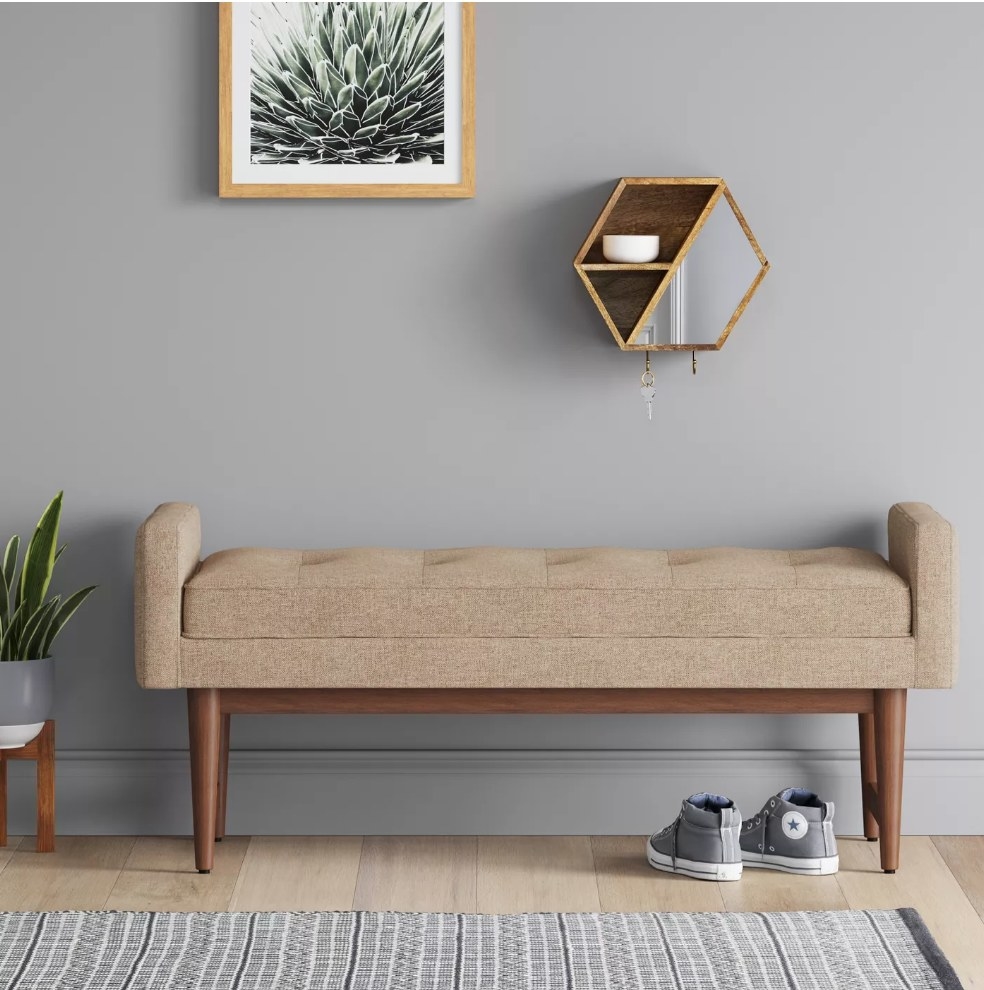 A tan, mid-century modern settee bench in a foyer