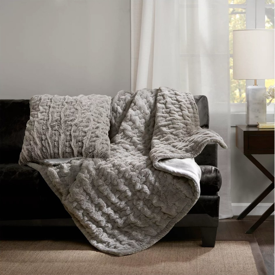 A 50&quot; x 60&quot;, gray faux-fur throw blanket draped over a couch