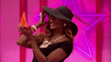 a gif of a drag queen on &quot;RuPaul&#x27;s Drag Race&quot; looking in a compact mirror 