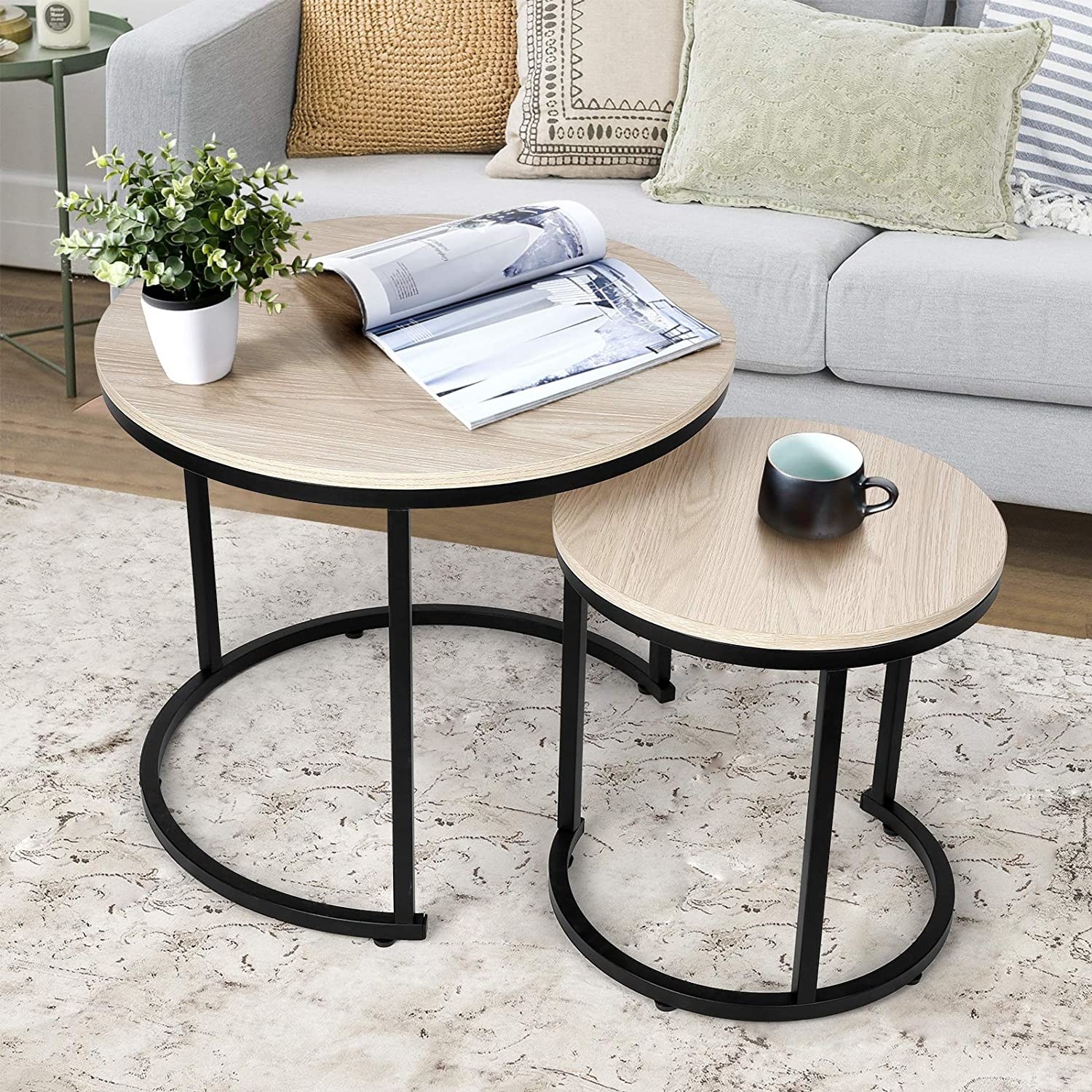 black and light wood round nesting tables next to a gray couch