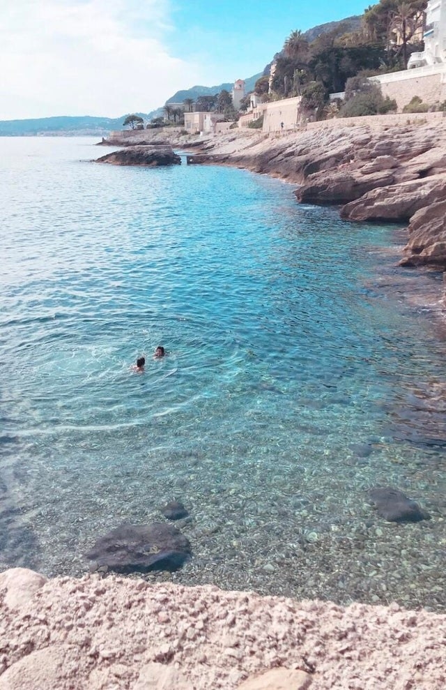 People swimming in a peaceful, clear-blue cove in Southern France