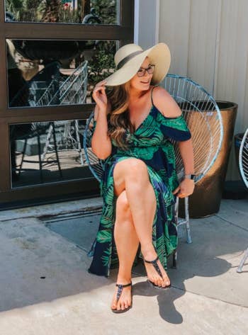 Reviewer sitting in green leaf print maxi dress with floppy hat