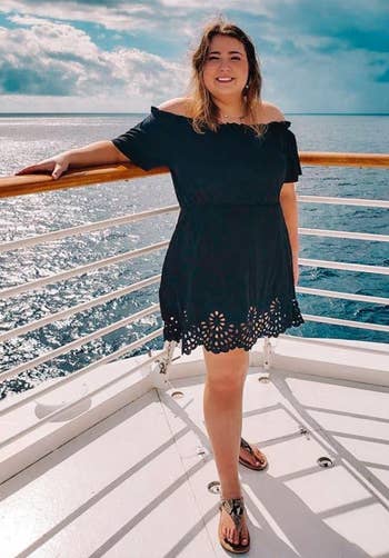 Reviewer posing on a boat in black mini dress with laser cut hem
