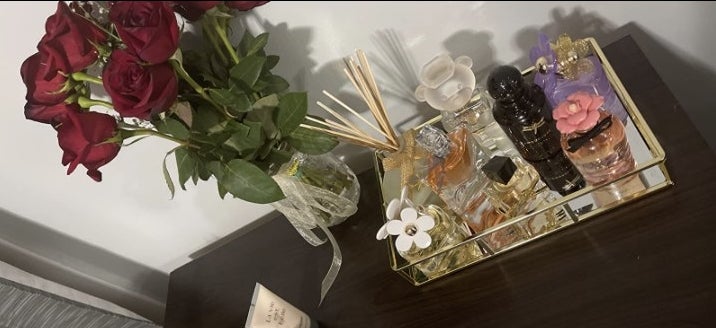 a reviewer showcasing the tray filled with luxury perfumes 