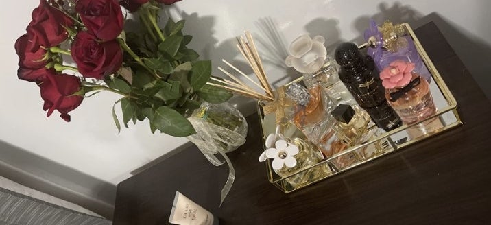 a reviewer showcasing the tray filled with luxury perfumes