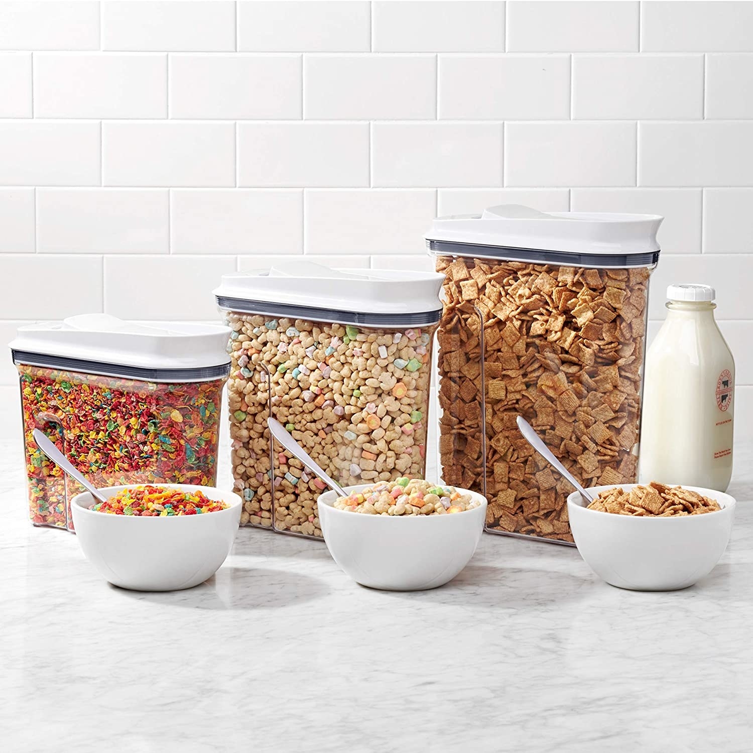 Three containers filled with cereral with filled cereal bowls in front of them