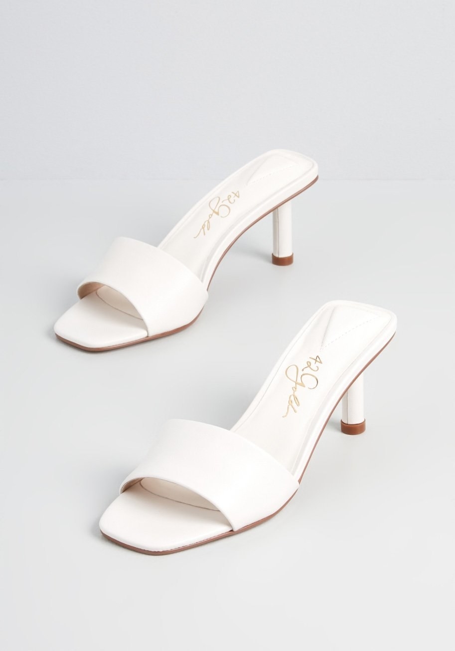 A pair of white sandal mules